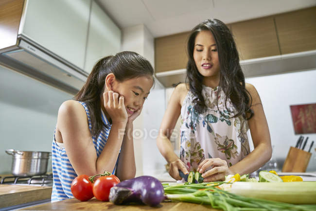 Asian mother and daughter cooking together at kitchen — Stock Photo