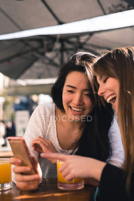 Duas belas amigas usando o smartphone juntas — Fotografia de Stock