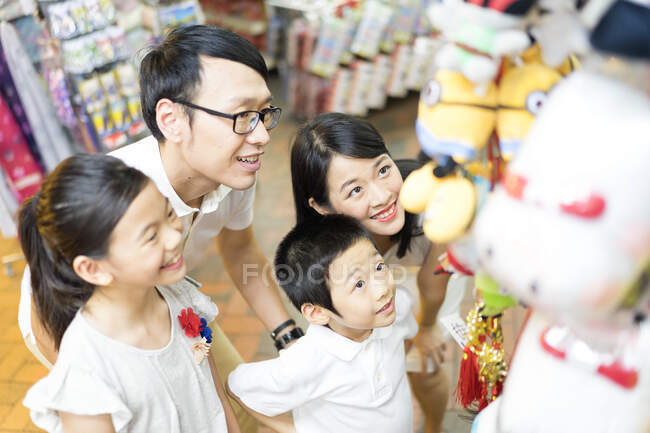 Familia asiática joven junto en el centro comercial mirando juguetes - foto de stock
