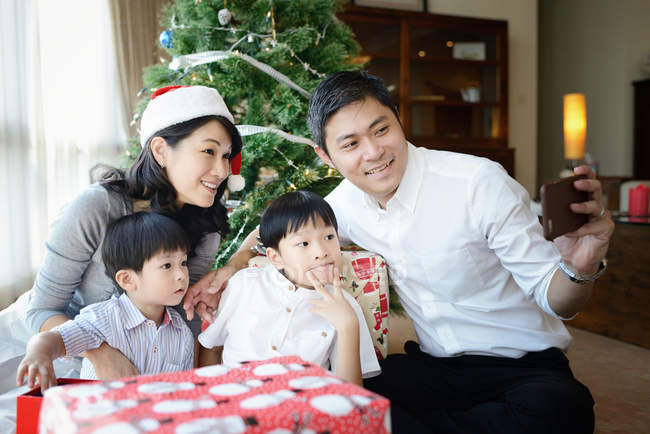 Happy young asian family taking selfie at christmas table — Stock Photo