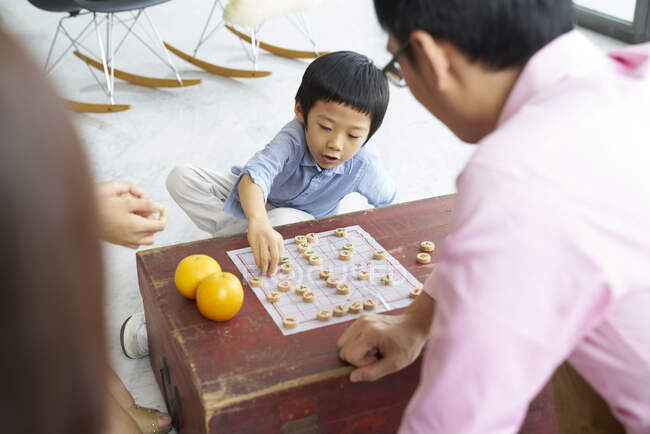 Familia asiática feliz pasar tiempo juntos y jugando juego de mesa - foto de stock