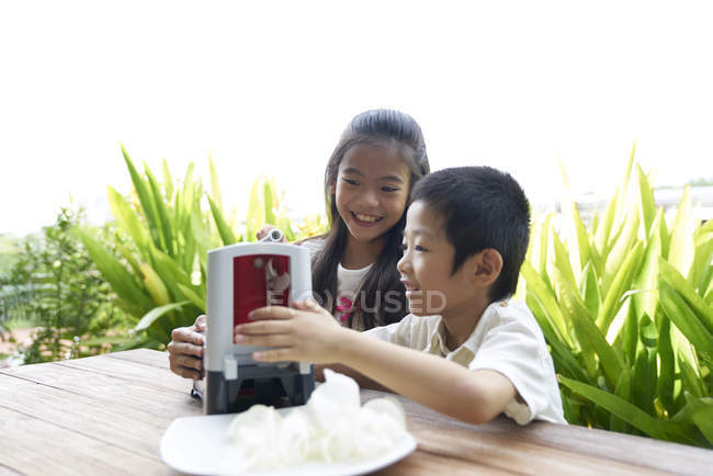 Feliz asiático hermanos haciendo arroz chips juntos - foto de stock