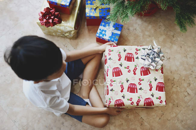 Ragazzo felice che celebra il Natale e disfa i regali a casa — Foto stock
