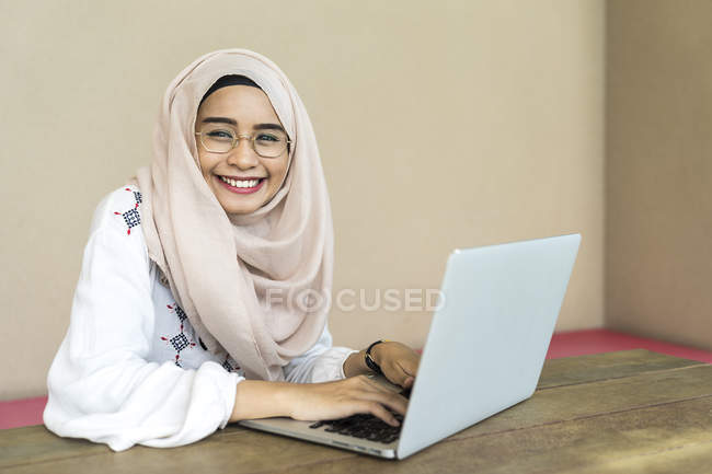 Jovem asiático muçulmano mulher usando laptop dentro de casa — Fotografia de Stock