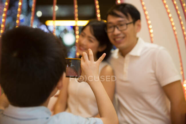 Filho tira uma foto de seus pais com um telefone — Fotografia de Stock