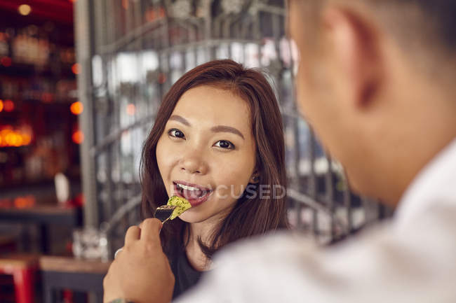 Young attractive asian couple having date in cafe, man feeding woman — Stock Photo