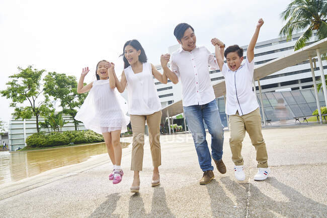Glückliche asiatische Familie, die zusammen geht und Händchen hält — Stockfoto