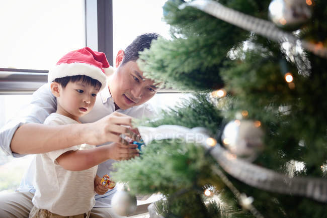 Happy asian family celebrating Christmas together at home and decorating fir tree — Stock Photo