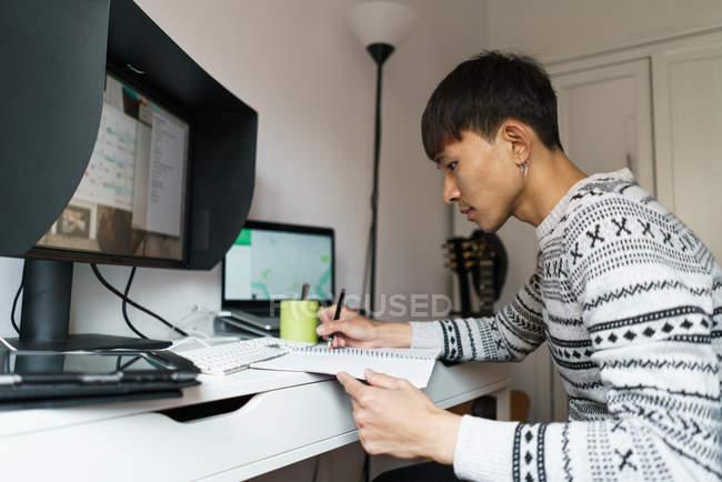 Young adult asian man working at home — Stock Photo