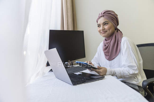 Femme musulmane travaillant avec un ordinateur portable de la maison — Photo de stock