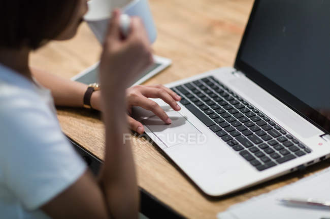 Image recadrée de la femme en utilisant un ordinateur portable au bureau — Photo de stock