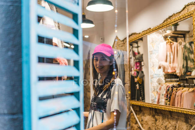 Молодая привлекательная азиатская женщина в розовой кепке в магазине — стоковое фото
