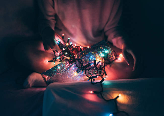 Immagine ritagliata di donna che si rilassa a casa con ghirlanda di Natale — Foto stock