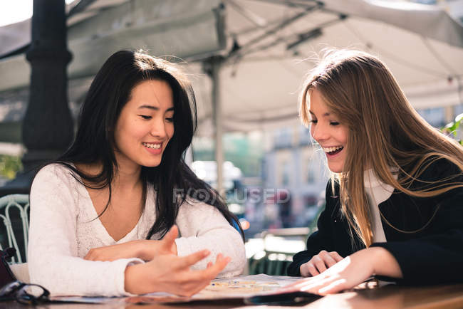 Дві красиві друзі-жінки дивляться на карту в кафе — стокове фото