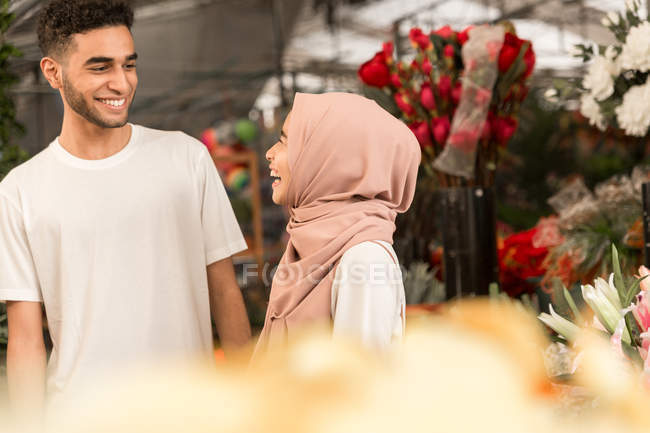 Young muslim couple in flower shop smiling at each other — Stock Photo