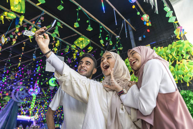 Eine Gruppe von Freunden macht ein Selfie gegen die Hari Raya Dekorationen. — Stockfoto