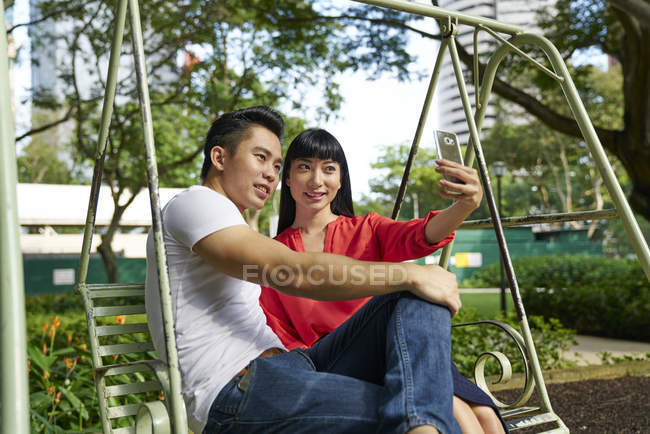 Giovane coppia asiatica scattare selfie su smartphone su swing — Foto stock