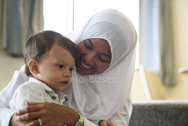 Madre en Hijab jugando con su hijo en el salón - foto de stock