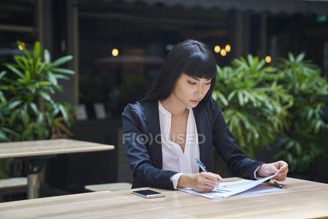 Young attractive asian businesswoman working in cafe — Stock Photo