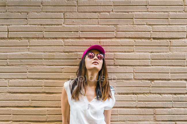 Junge attraktive asiatische Frau mit Sonnenbrille und rosa Kappe — Stockfoto