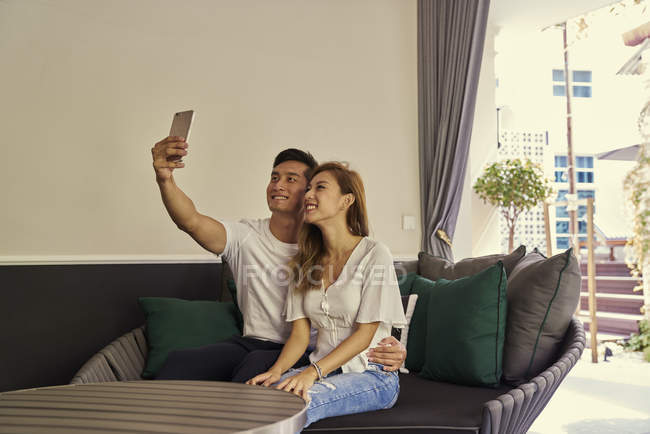 Feliz joven asiático pareja tomando selfie en casa - foto de stock