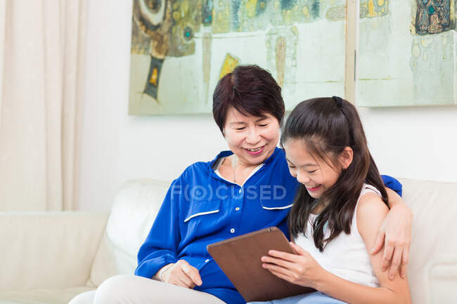 Großmutter und Enkelkind nutzen gemeinsam ein Tablet. — Stockfoto