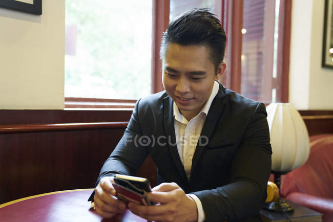 Jeune homme d'affaires beau en utilisant smartphone dans le bureau — Photo de stock