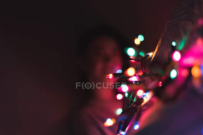 Молодая азиатка отдыхает дома с рождественской гирляндой — стоковое фото