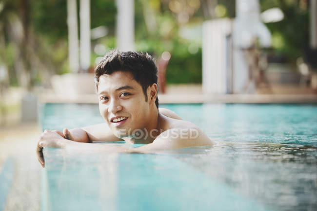 Молодой привлекательный азиатский мужчина расслабляется в бассейне — стоковое фото