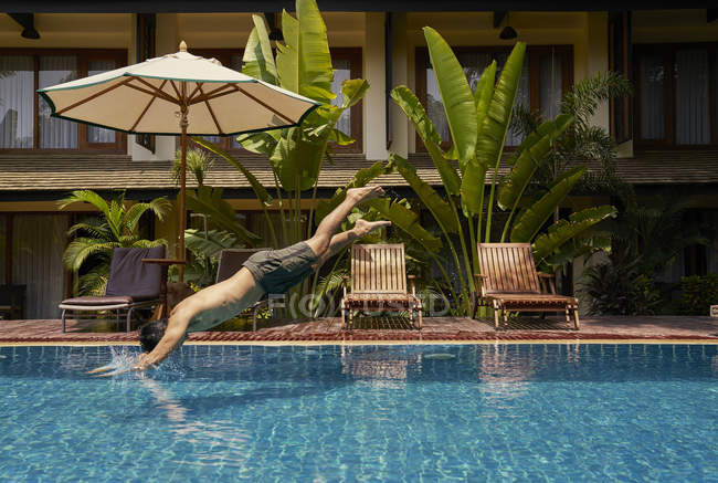 Junger Mann springt in den Pool, Seitenansicht — Stockfoto