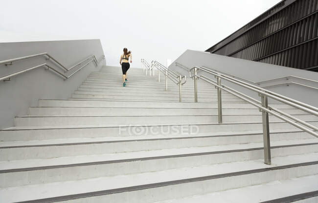 Un giovane asiatico, corridore femminile sta correndo su per una scala a Singapore
. — Foto stock