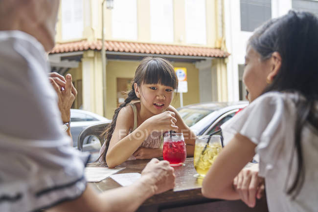 Happy asian family drinking beverages in street cafe — Stock Photo