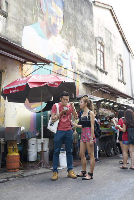 Glücklich junge asiatische Paar essen in lokalen Markt — Stockfoto