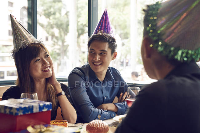 Happy young asian friends celebrating christmas together in cafe — Stock Photo