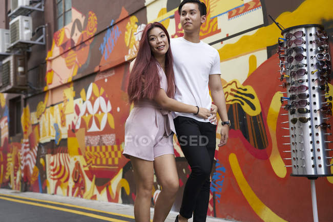 Young attractive asian couple hugging and walking on street — Stock Photo