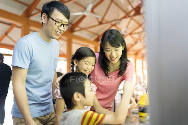 Familia asiática joven junto comiendo en la cafetería - foto de stock