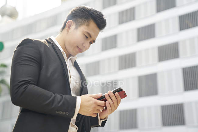 Молодий азіатський успішний бізнесмен використовує смартфон — стокове фото