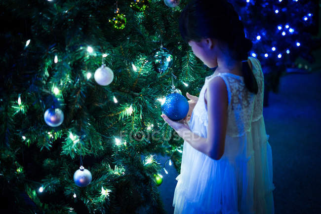 Счастливая азиатская девушка играет с пузырьком возле елки в парке развлечений на Рождество — стоковое фото
