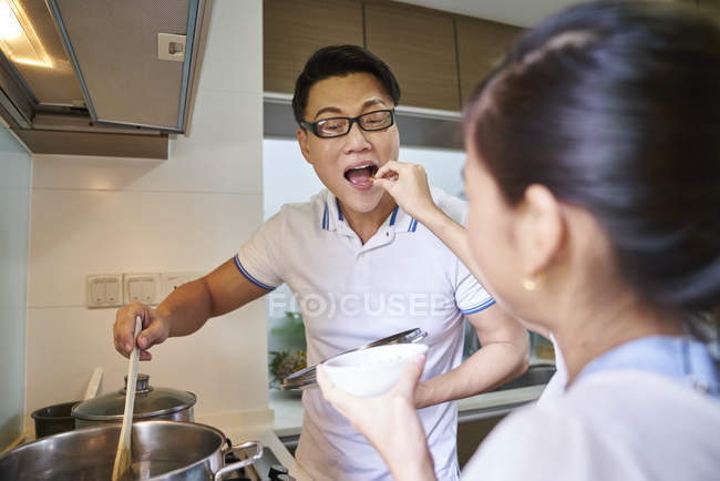 Little girl feeding father on kitchen — Stock Photo