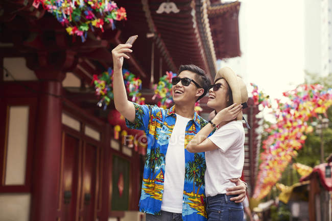 Young asian couple having fun at Chinese New Year festival and taking selfie — Stock Photo