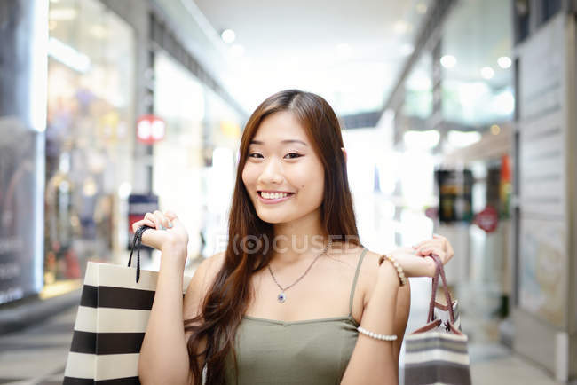 Jeune attrayant asiatique femme avec shopping sacs — Photo de stock