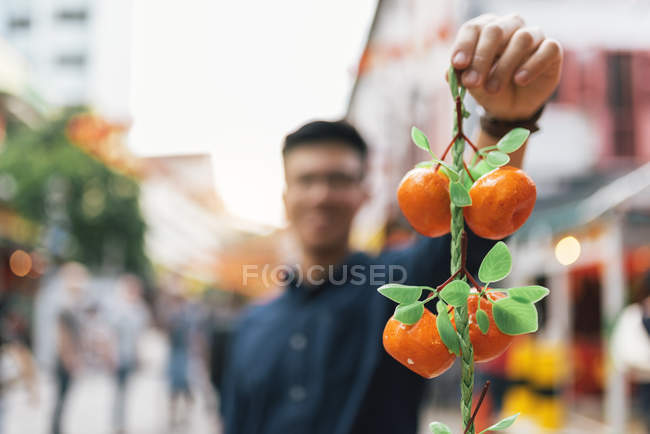 Молодий азіатський чоловік показує мандарини на камеру — стокове фото