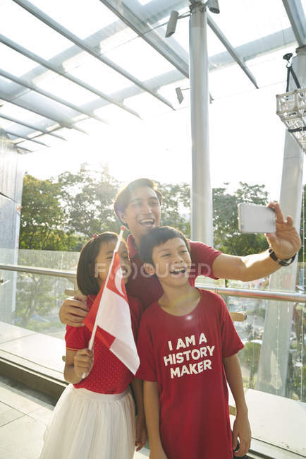 Famiglia felice che festeggia singapores la giornata nazionale — Foto stock