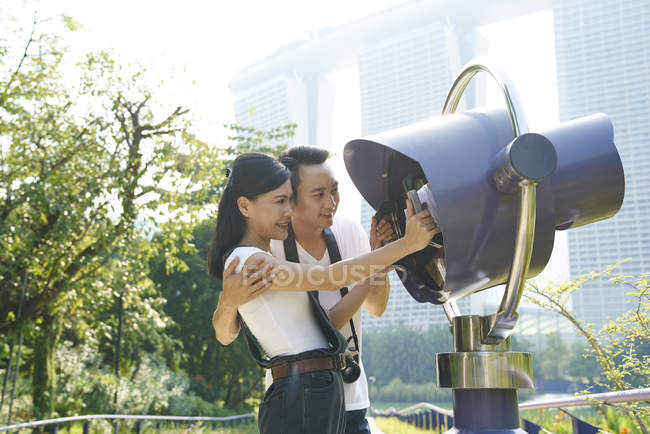 Schönes Paar mit dem elektronischen Fernglas in den Gärten an der Bucht — Stockfoto