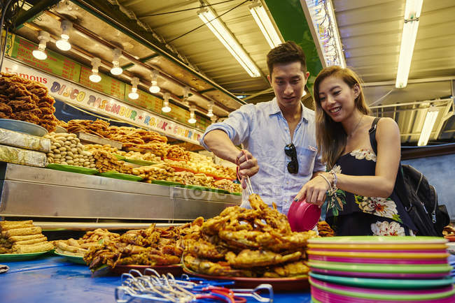 Feliz jovem asiático casal tomando alimentos no mercado — Fotografia de Stock