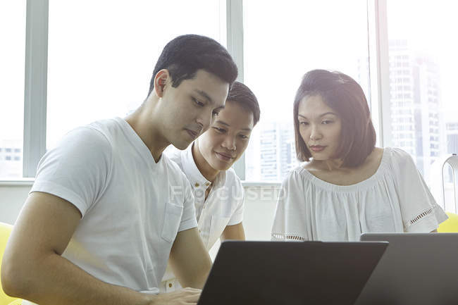 Jovem asiático pessoas de negócios trabalhando com laptops no escritório moderno — Fotografia de Stock
