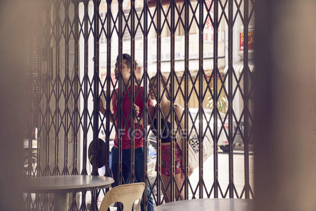 Jovem atraente asiático casal juntos olhando para o café através de cerca — Fotografia de Stock