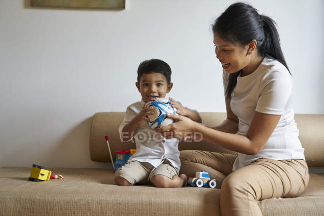Asiático madre y hijo vinculación más juguetes en el sofá - foto de stock