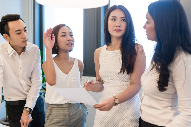 Jóvenes asiáticos colegas trabajando juntos en moderno oficina - foto de stock