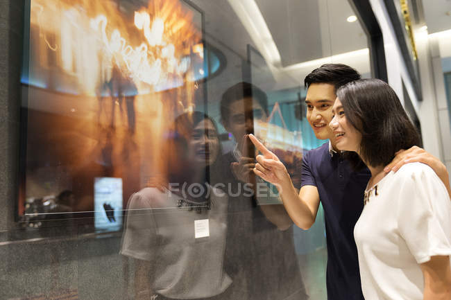 Jeune attrayant asiatique couple ensemble shopping et regarder sur tv écran — Photo de stock